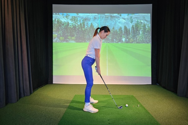 Girl playing golf on screen and golf simulator